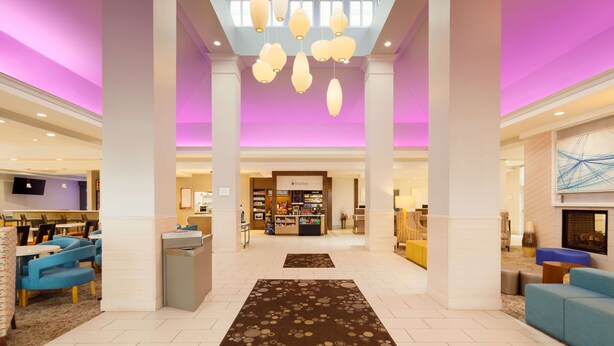 A spacious lobby with a high ceiling, a central reception desk, and a seating area with blue chairs. - Hilton Garden Inn Cincinnati Blue Ash (Cincinnati)