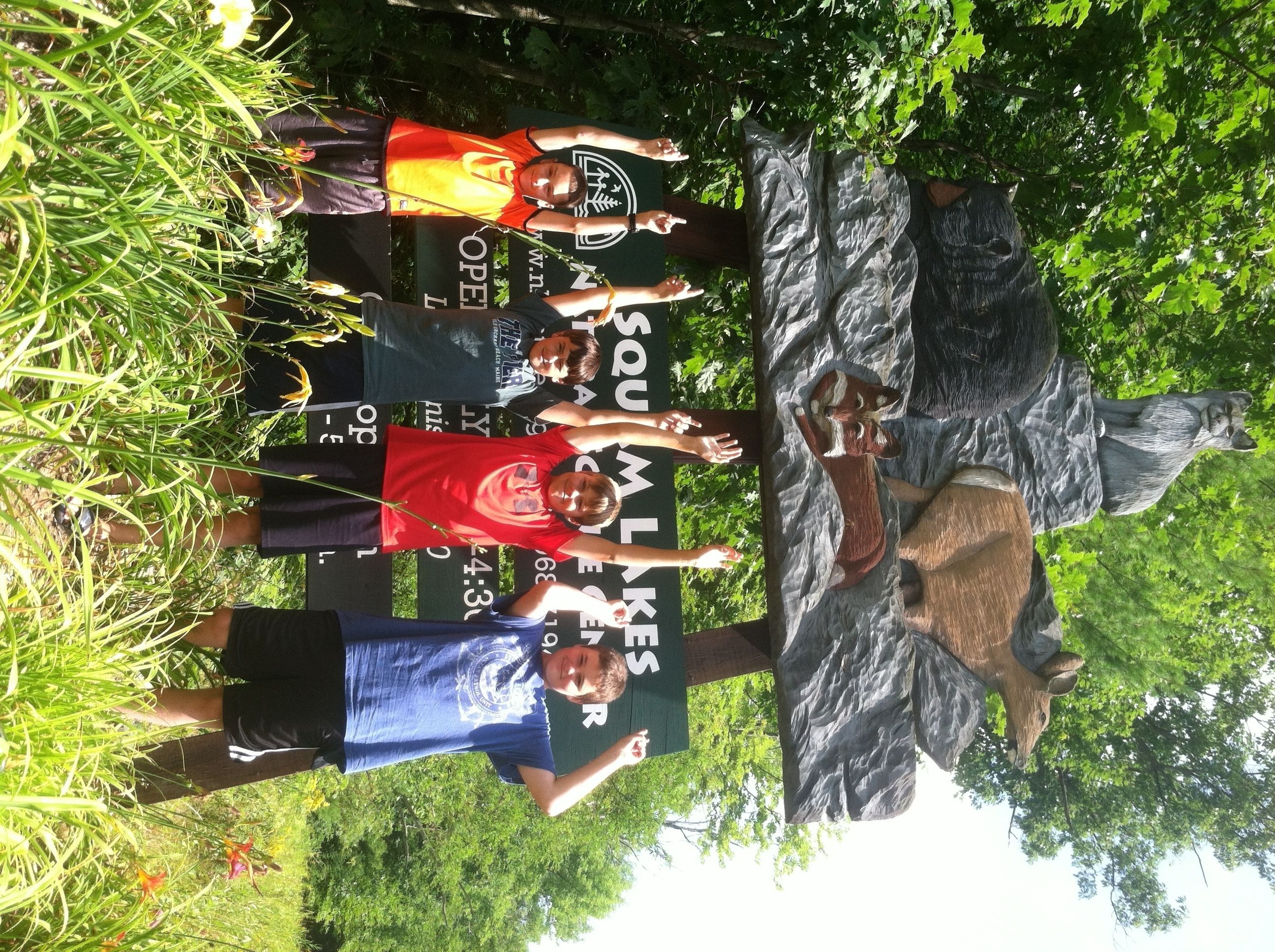 A group of people standing in front of a large rock sculpture in a natural setting.