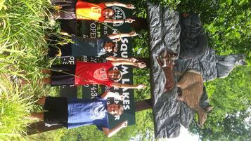 A group of people standing in front of a large rock sculpture in a natural setting.