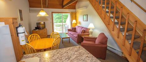 A cozy interior with a wooden staircase, a dining area with a marble table, and a living room with a sofa and lamps.