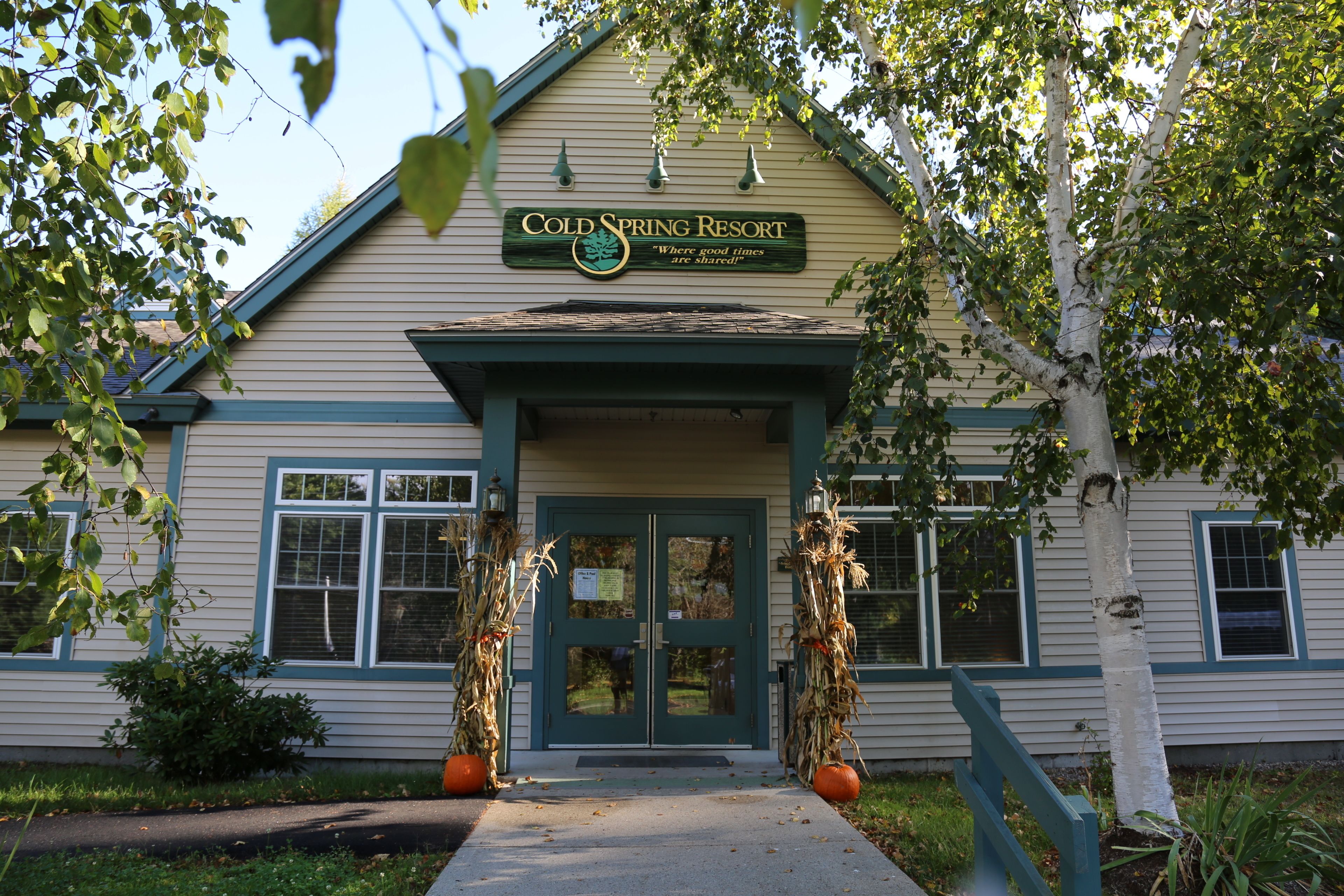 A building labeled "Cold Spring Resort" with a green door and windows, a porch, and two decorative trees.