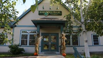A building labeled "Cold Spring Resort" with a green door and windows, a porch, and two decorative trees.