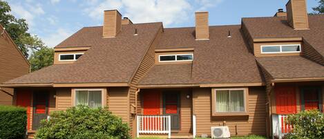 A row of two-story houses with a central walkway, each with a small front porch and a window.