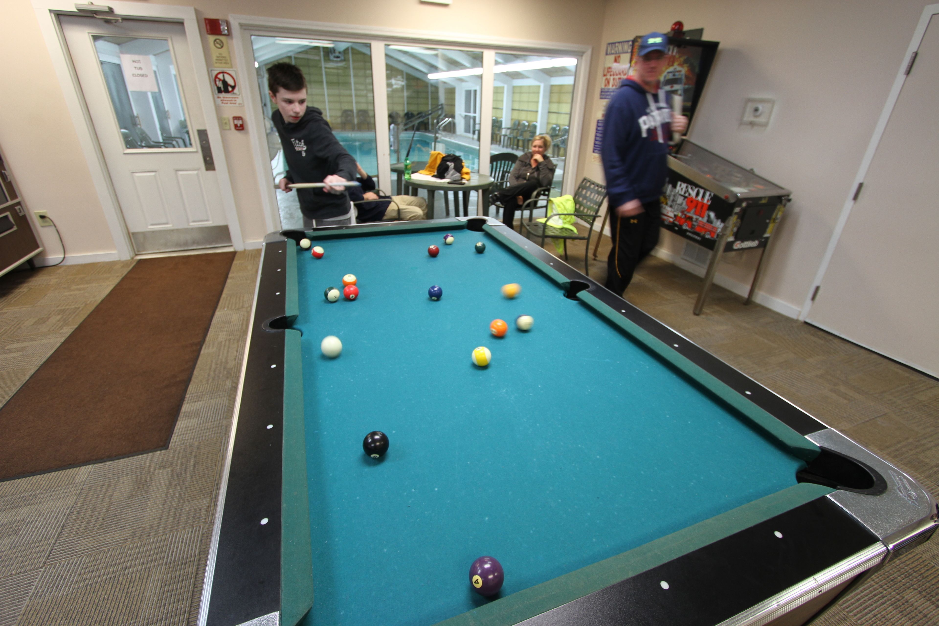 Een pooltafel met ballen, een deur en iemand die poolt.