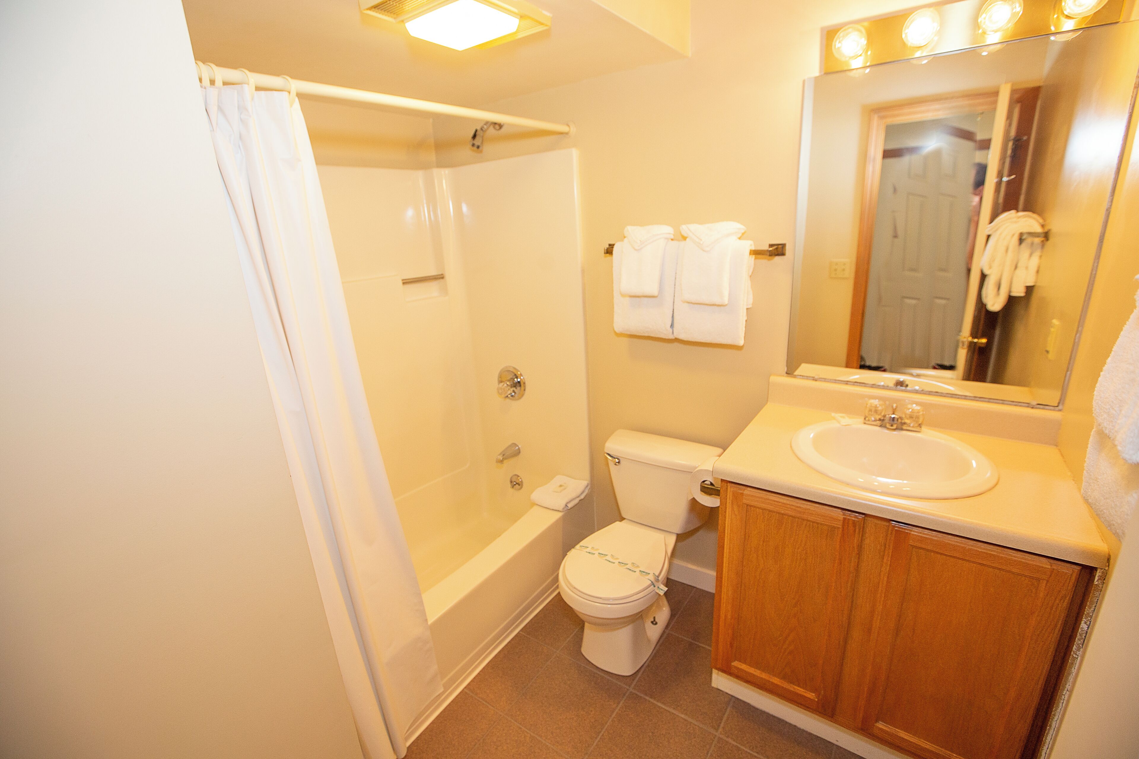 A bathroom with a bathtub, toilet, sink, and a mirror.
