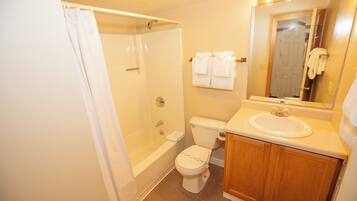 A bathroom with a bathtub, toilet, sink, and a mirror.