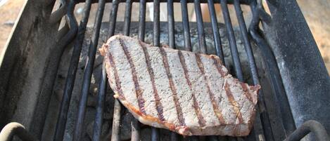 A grill with a steak being cooked.