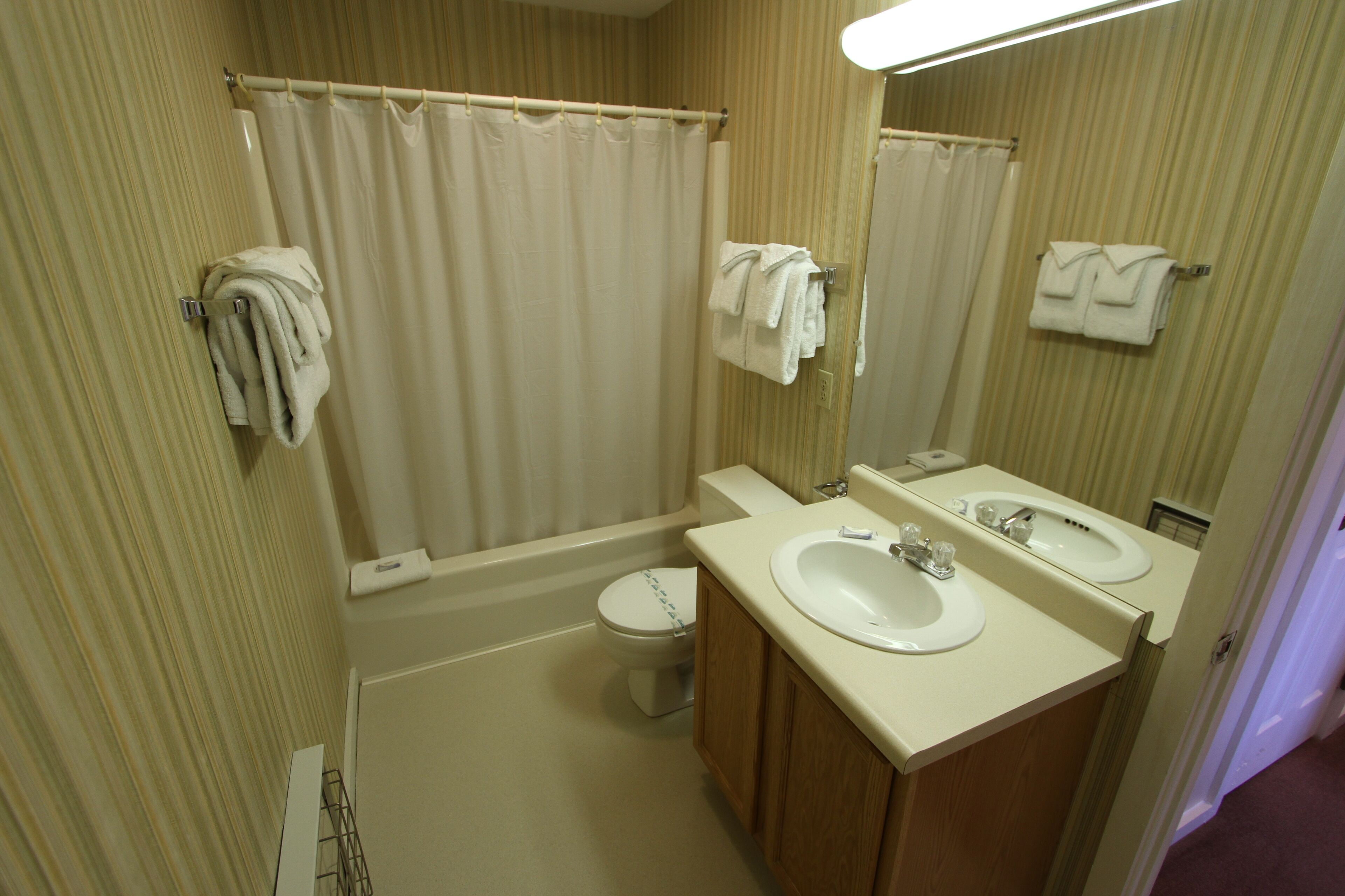 A standard hotel bathroom with a bathtub, toilet, and sink.