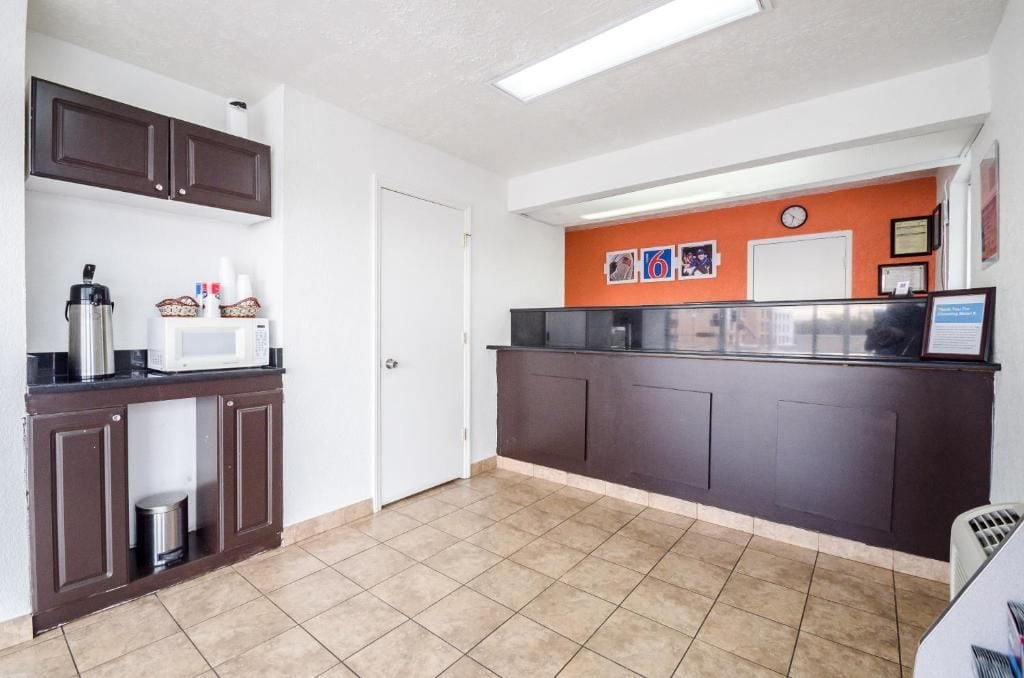 A kitchen with dark cabinets, a microwave, a coffee maker, and a trash can.