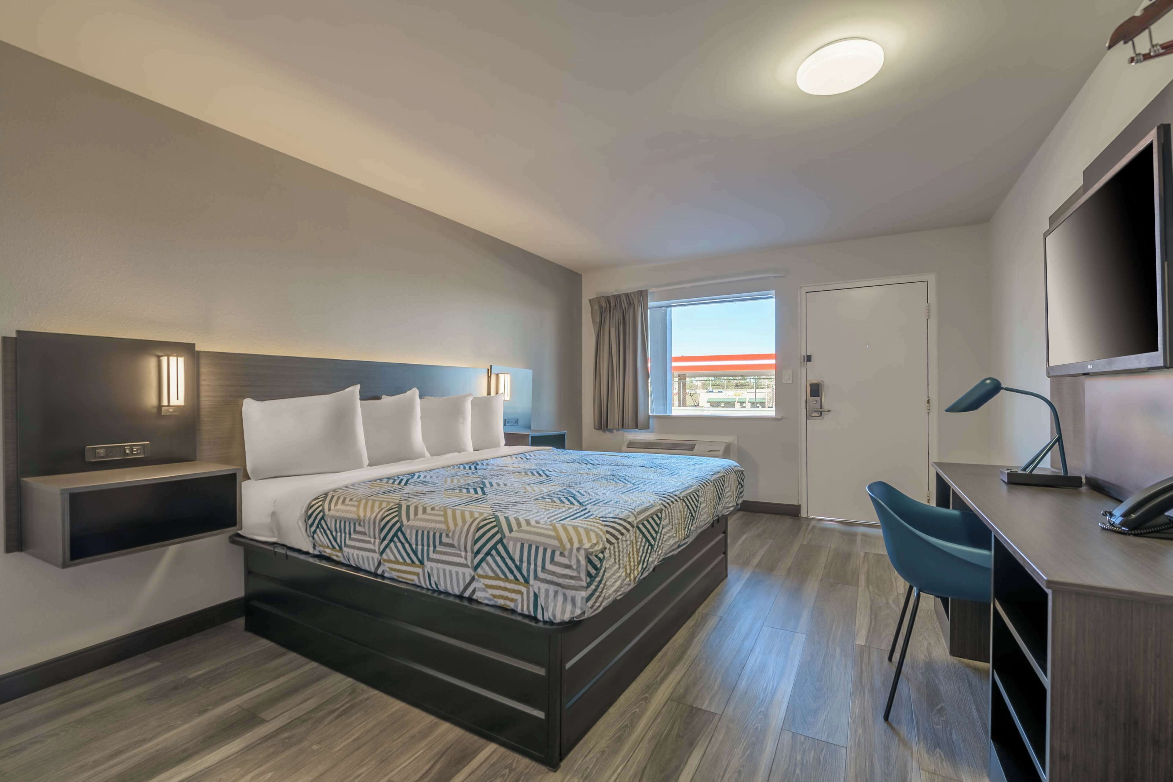 Une chambre d’hôtel moderne, dotée d’un grand lit, d’un bureau et d’une télévision.