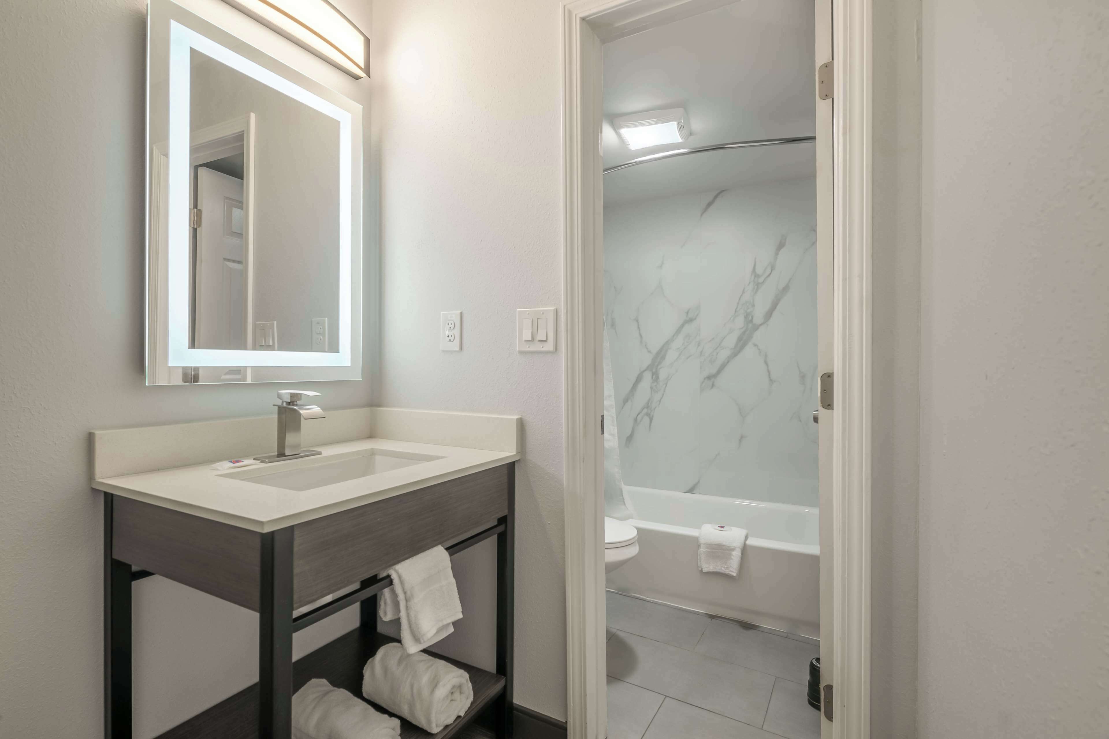 A modern bathroom with a white sink, dark vanity, and a glass shower enclosure.