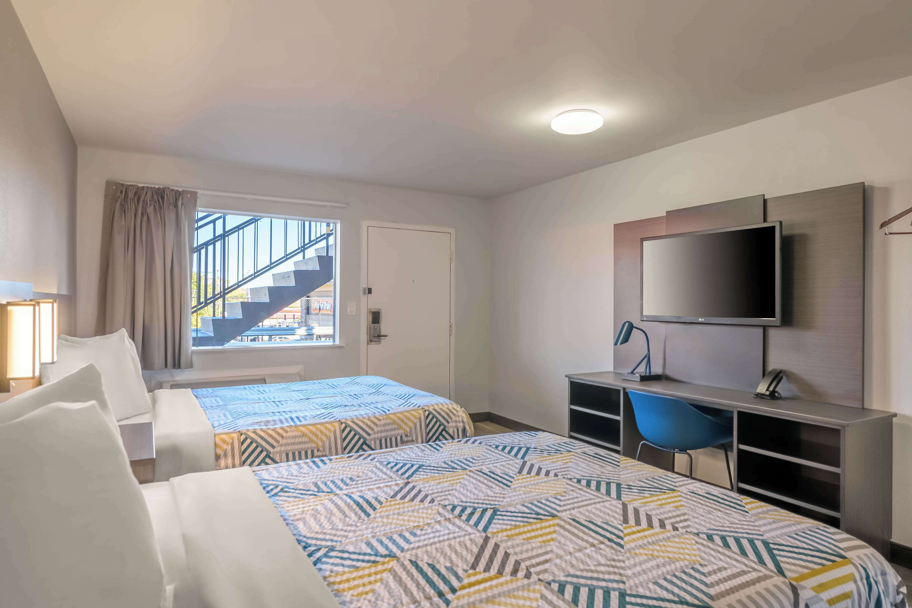 Une chambre d’hôtel avec deux lits, une télévision, un bureau et une chaise.