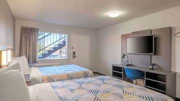 Une chambre d’hôtel avec deux lits, une télévision, un bureau et une chaise.