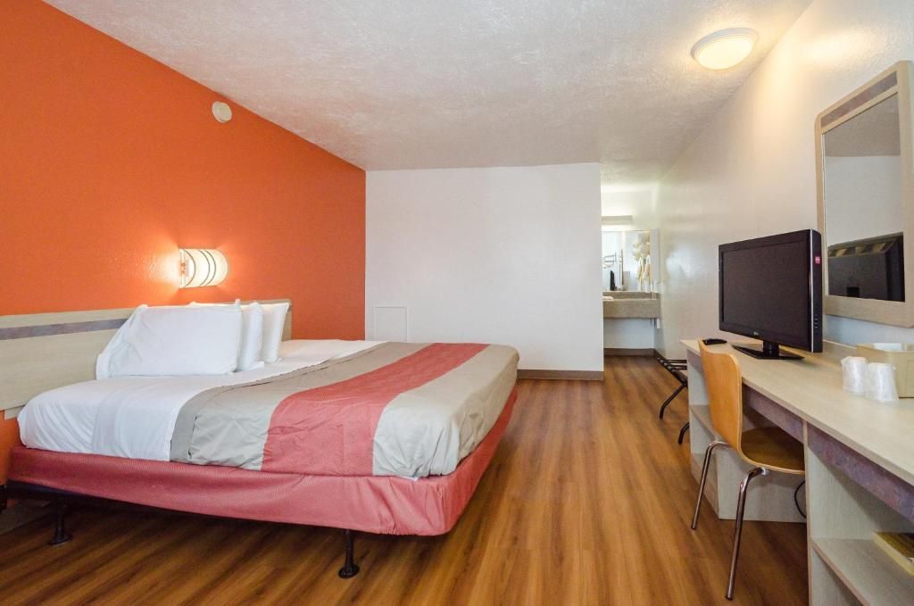 A hotel room with a bed, a desk with a computer, and a chair.
