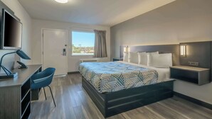 Ein modernes Hotelzimmer mit Bett, Schreibtisch, Stuhl und Fernseher.