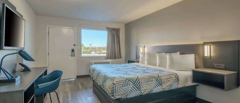 Una habitación de hotel moderna con cama, escritorio, silla y televisión.