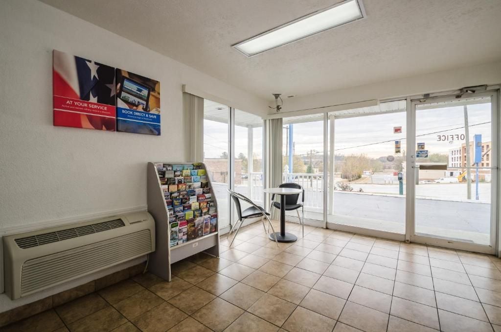 A hotel lobby with a self-service kiosk, a seating area, and large windows offering a view of the street.