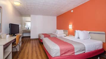 Una habitación de hotel con dos camas, un escritorio, una silla, un televisor y un baño a la vista.
