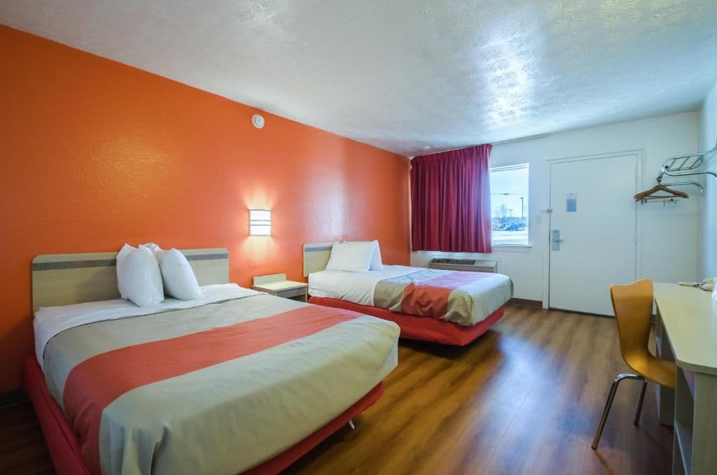 Camera d'albergo con due letti, una scrivania e una sedia.