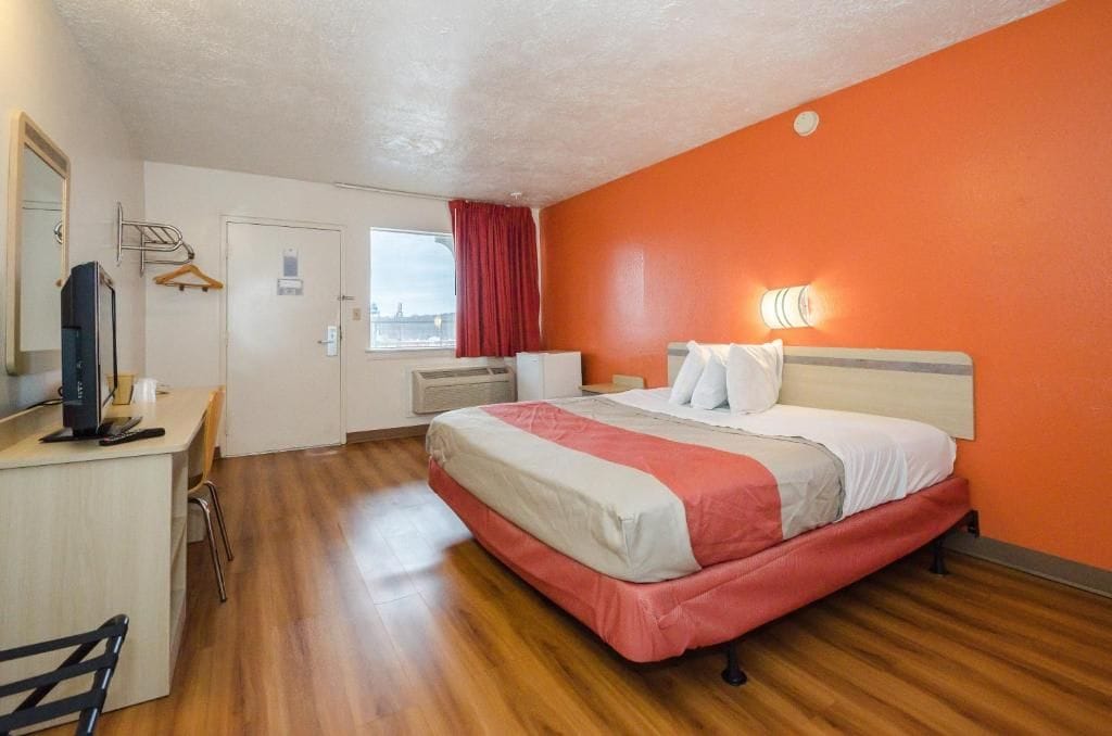 Una habitación de hotel con una cama, un escritorio, una silla, un televisor y una ventana con vistas.