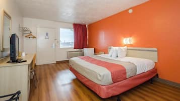 Una habitación de hotel con una cama, un escritorio, una silla, un televisor y una ventana con vistas.