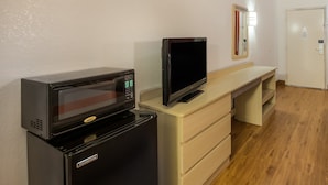 Une petite cuisine équipée d’un four à micro-ondes, d’un réfrigérateur et d’un téléviseur à écran plat, le tout installé sur un comptoir en bois.