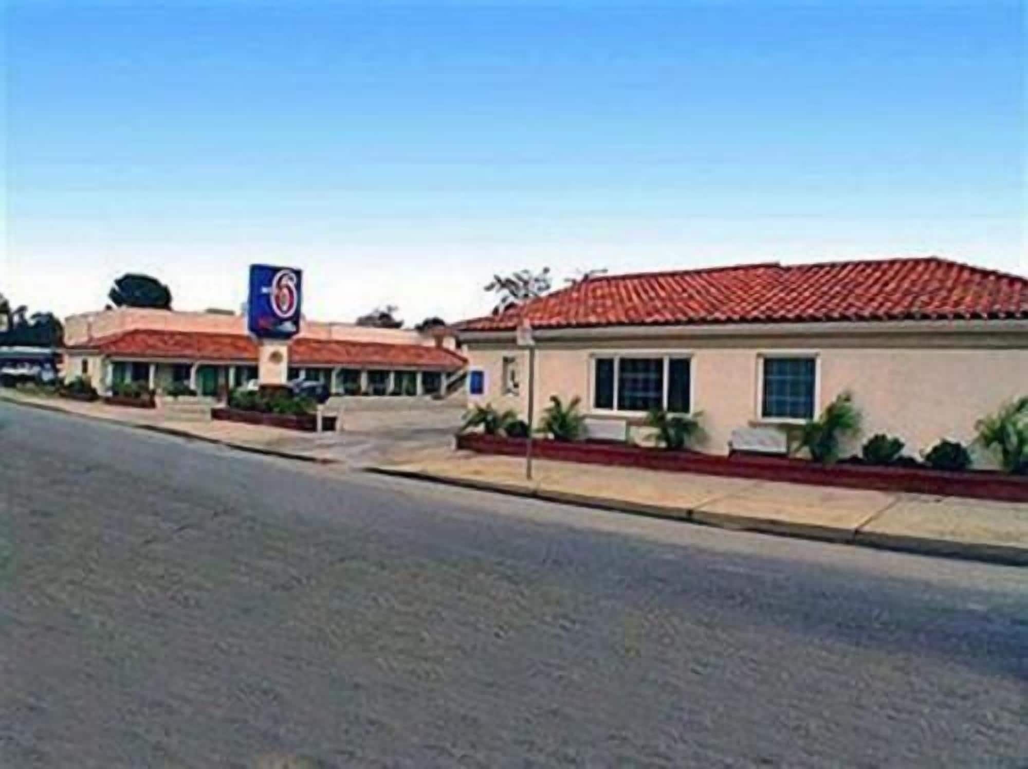A motel with a red-tiled roof, a blue sign with a number, and a parking lot.