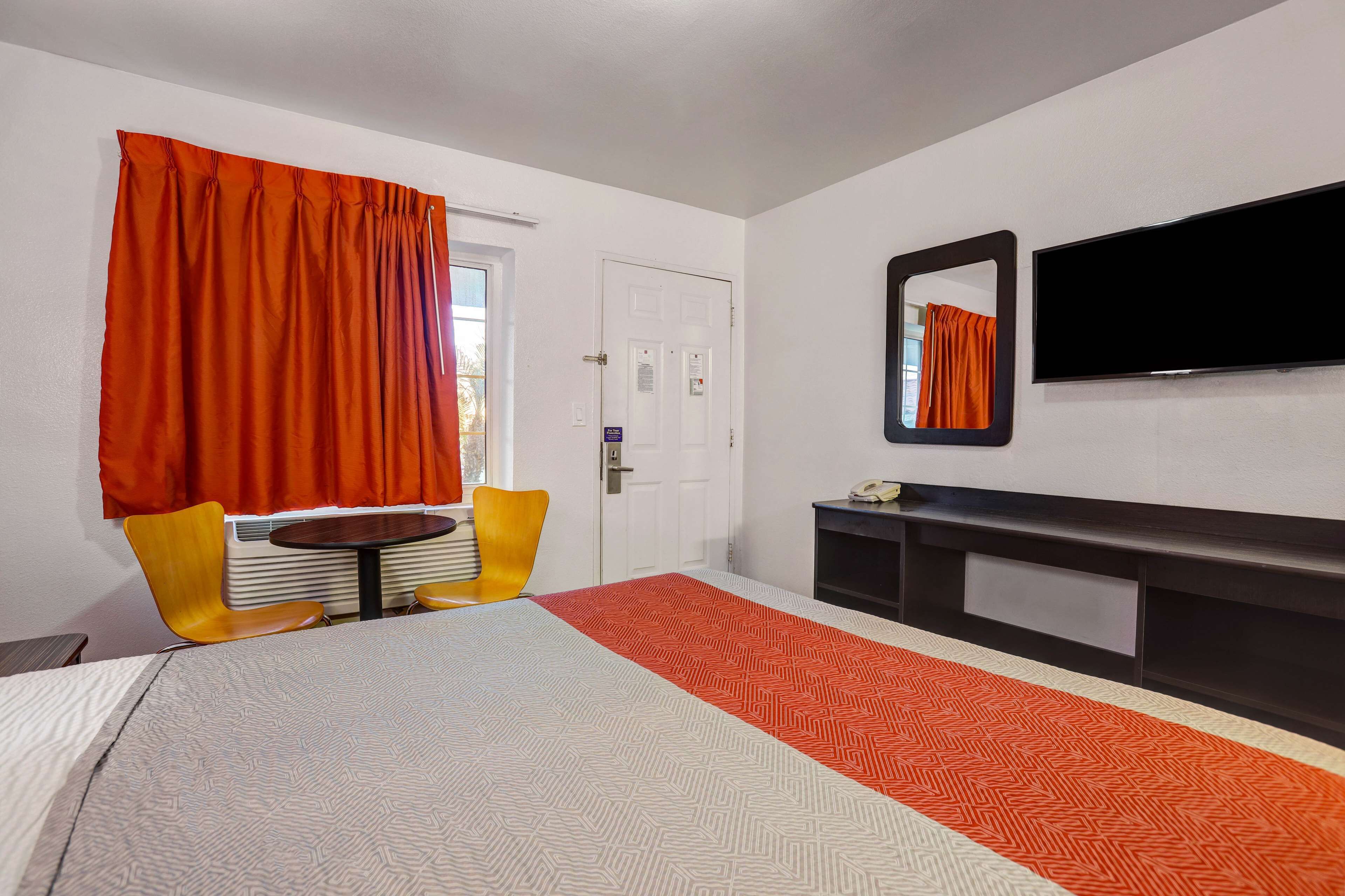 Una habitación de hotel con cama, televisión, escritorio y silla.