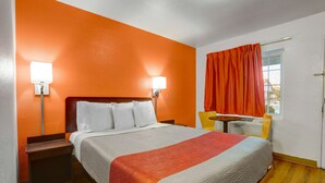 Una habitación de hotel con una cama, una mesita de noche, una mesa y una silla.