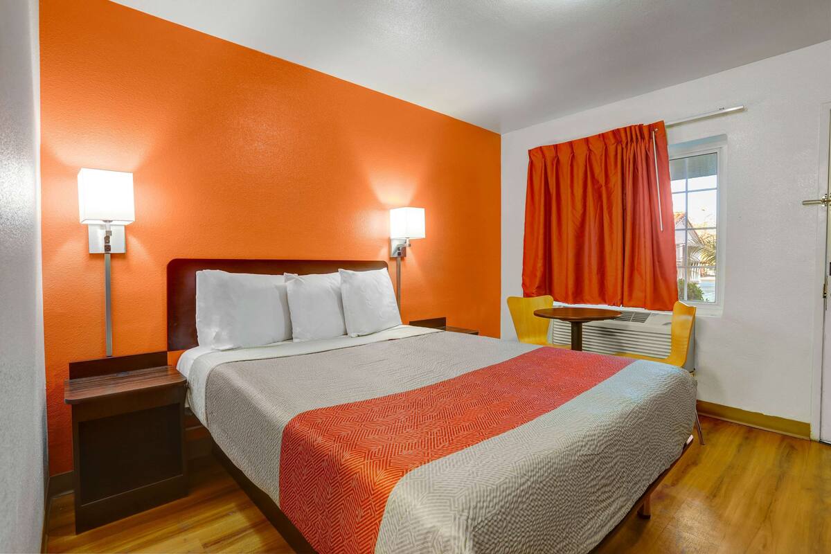 Una habitación de hotel con una cama, una mesita de noche, una mesa y una silla.