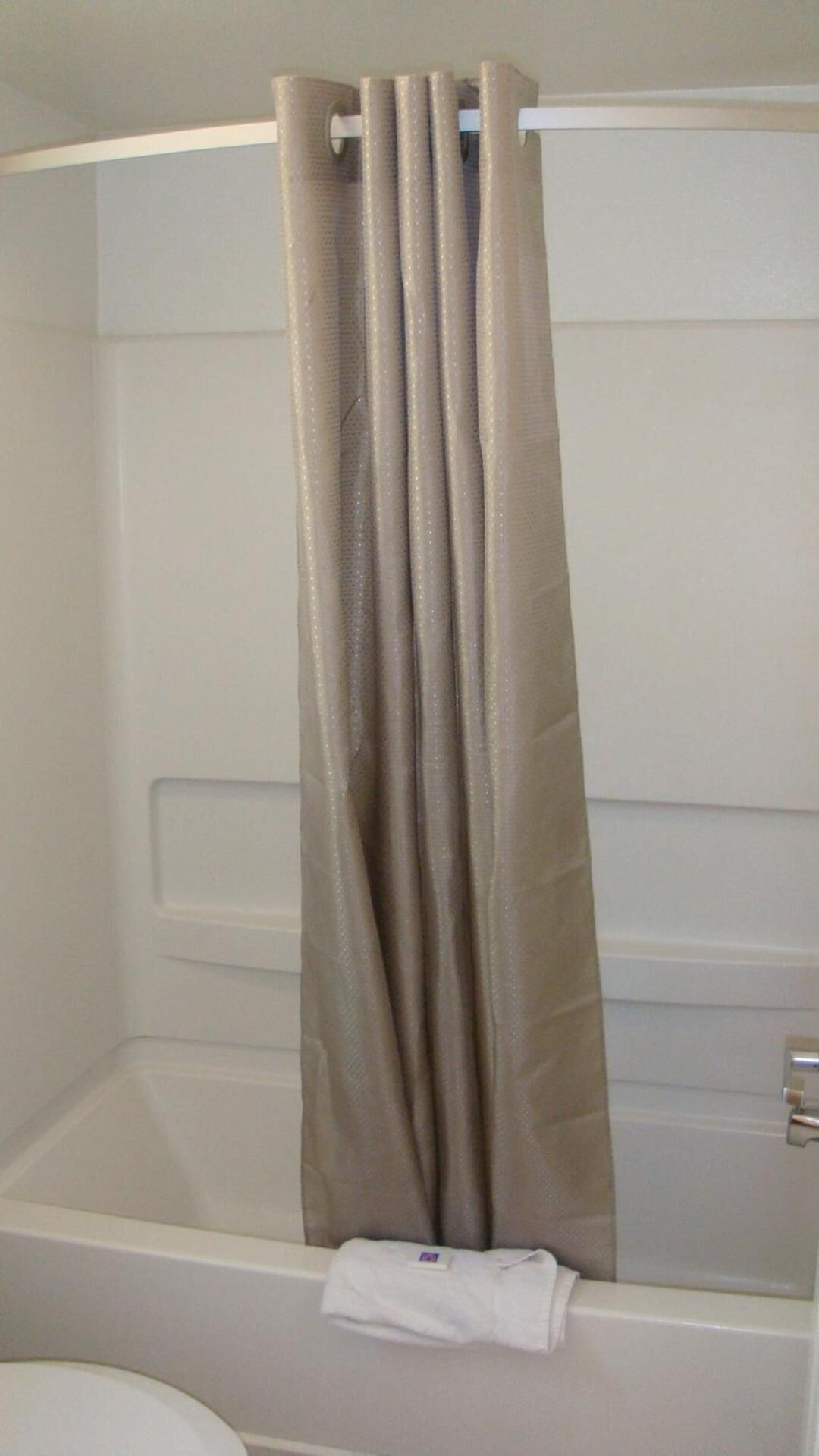 A bathroom with a bathtub, a shower curtain, and a towel on the floor.