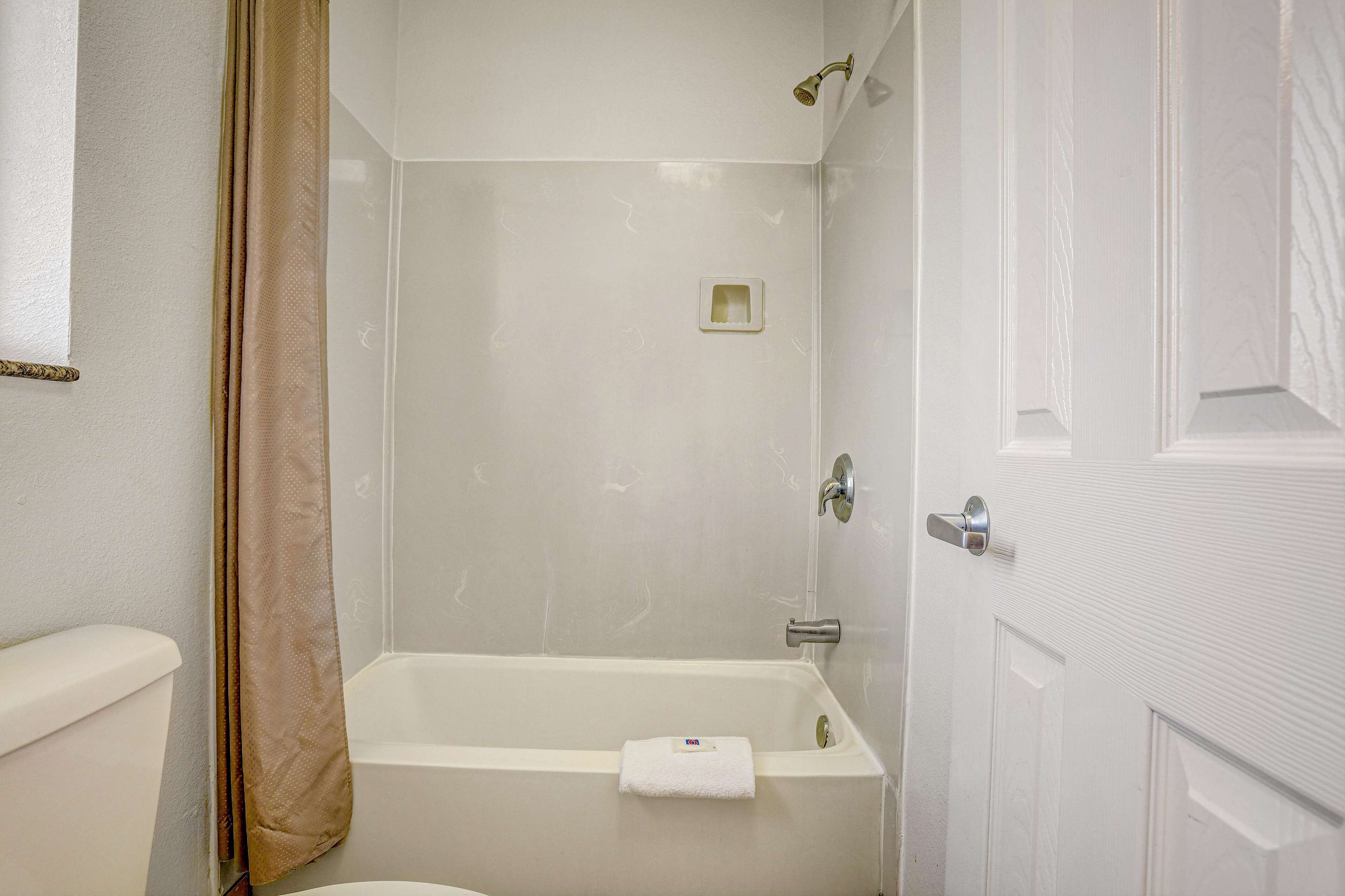 A bathroom with a bathtub, toilet, and shower curtain.