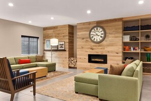 A modern living room with a sectional sofa, a wooden coffee table, a fireplace, and a bookshelf. - Country Inn & Suites by Radisson, Shreveport-Airport, LA (Shreveport)