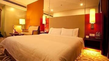 A hotel room with a large bed, a chair, a nightstand, and a wall-mounted lamp.