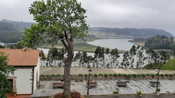 Vista a la orilla del río con un sendero de piedra, bancos y un árbol.