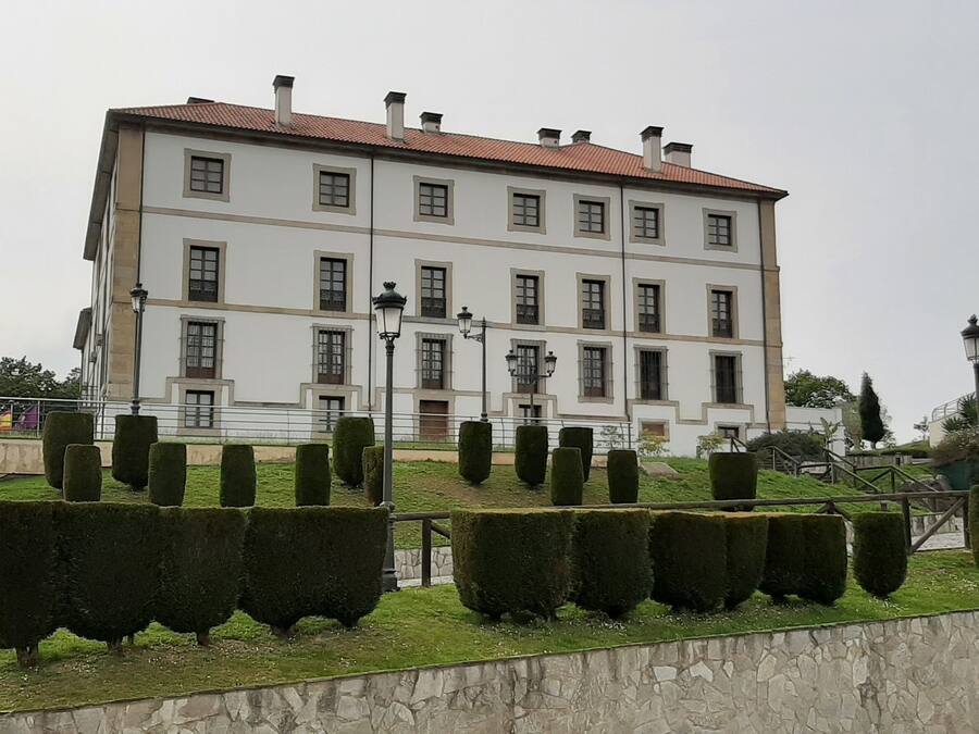 Un edificio grande e histórico con fachada simétrica, numerosas ventanas y una entrada central.