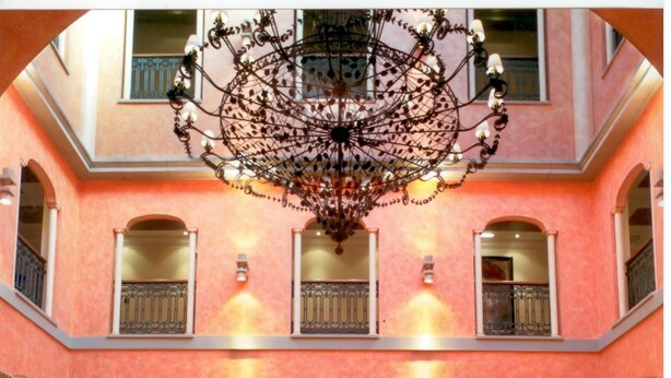 Un amplio vestíbulo con candelabro, varias zonas de descanso y una mesa central adornada con flores.