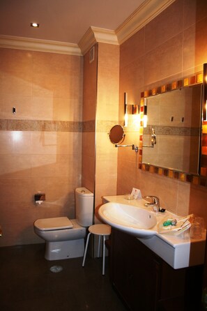 A bathroom with a toilet, bidet, sink, and mirror.