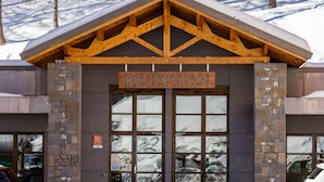 A reception area with a sign above the entrance, stone walls, and a view of snow-covered trees in the background. - Noemys Les Terrasses de Labrau  (Allos)