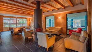 A modern living room with a fireplace, leather sofas, and a view of a pool. - Noemys Les Terrasses de Labrau  (Allos)