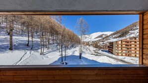 A view from a window of a building with a snow-covered landscape, trees, and a mountain in the background. - Noemys Les Terrasses de Labrau  (Allos)