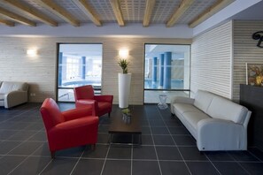 Ein modernes Interieur mit einer roten und weißen Sofagarnitur, einem Couchtisch und einem großen Fenster mit Blick auf einen Poolbereich.