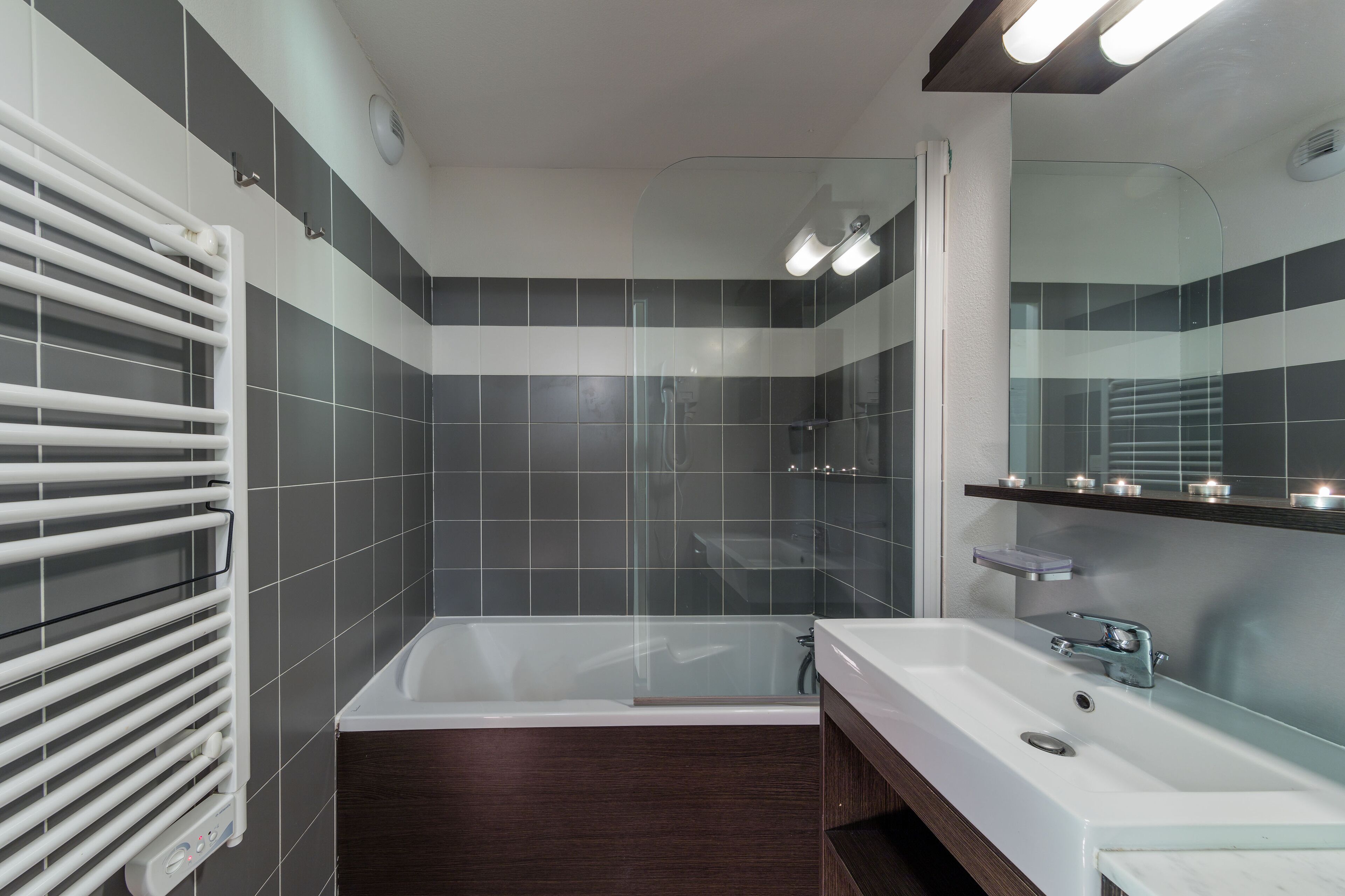 Une salle de bain moderne avec une baignoire, un grand miroir et une cabine de douche en verre.