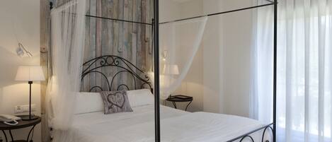 A four-poster bed with a canopy, a bedside table with a lamp, and a wall with a rustic wooden panel design.