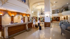 A spacious lobby with a reception desk, a chandelier, and a seating area with sofas. - Aquamare Beach Hotel & Spa (Geroskipou)