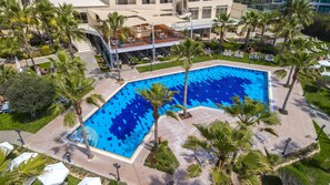 Una piscina techada, una piscina al aire libre, sombrillas