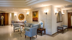A spacious lobby with a modern design, featuring a sofa, armchairs, a coffee table, and decorative wall art. - Aquamare Beach Hotel & Spa (Geroskipou)