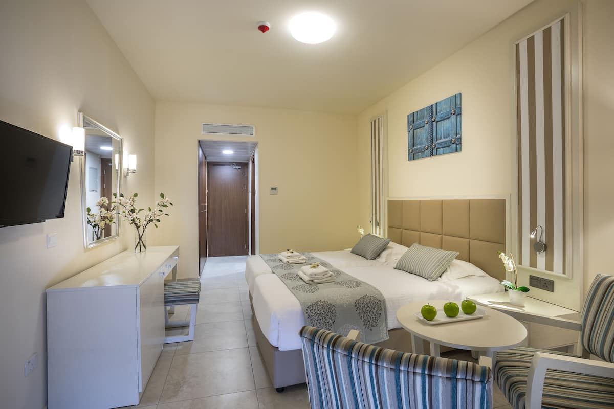 A hotel room with a bed, bedside table, chair, desk, and a television.