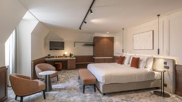 Une chambre d’hôtel moderne équipée d’un grand lit, d’un bureau, de deux fauteuils et d’une petite table.
