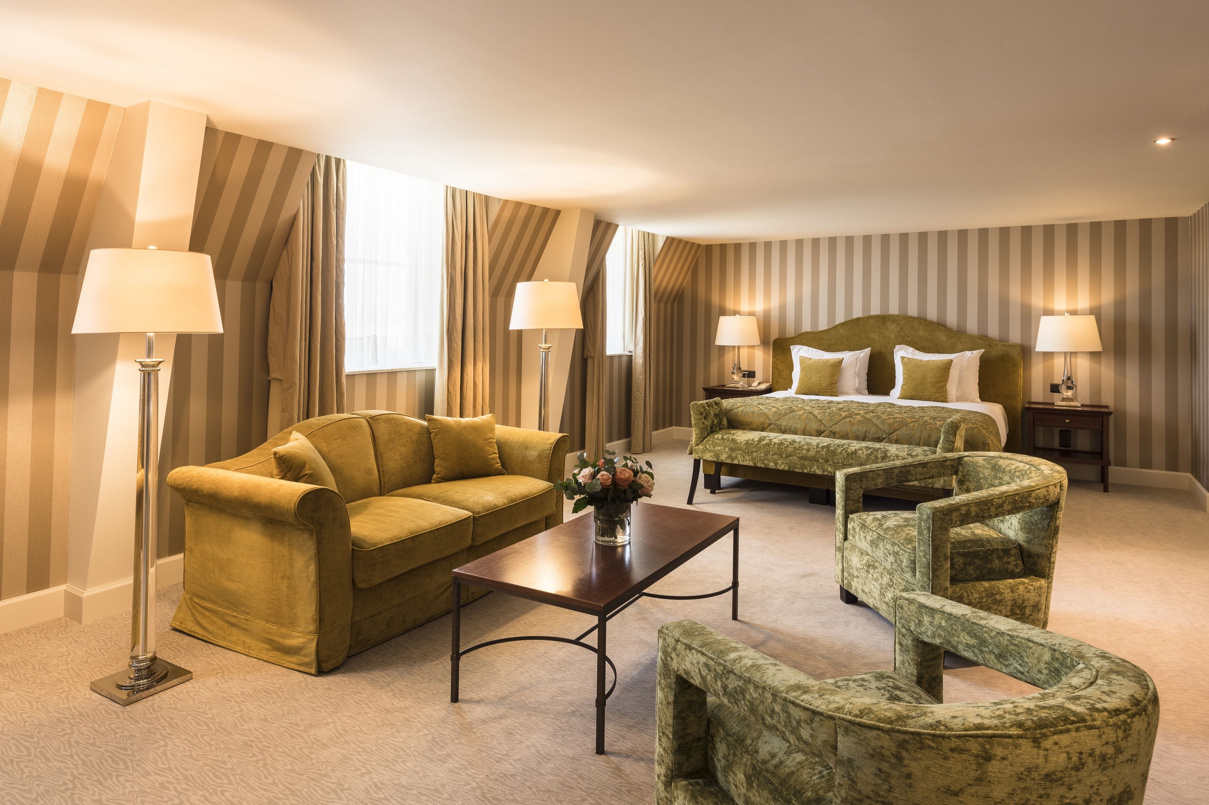 Une chambre d’hôtel avec un canapé, un lit, une table basse et une chaise.
